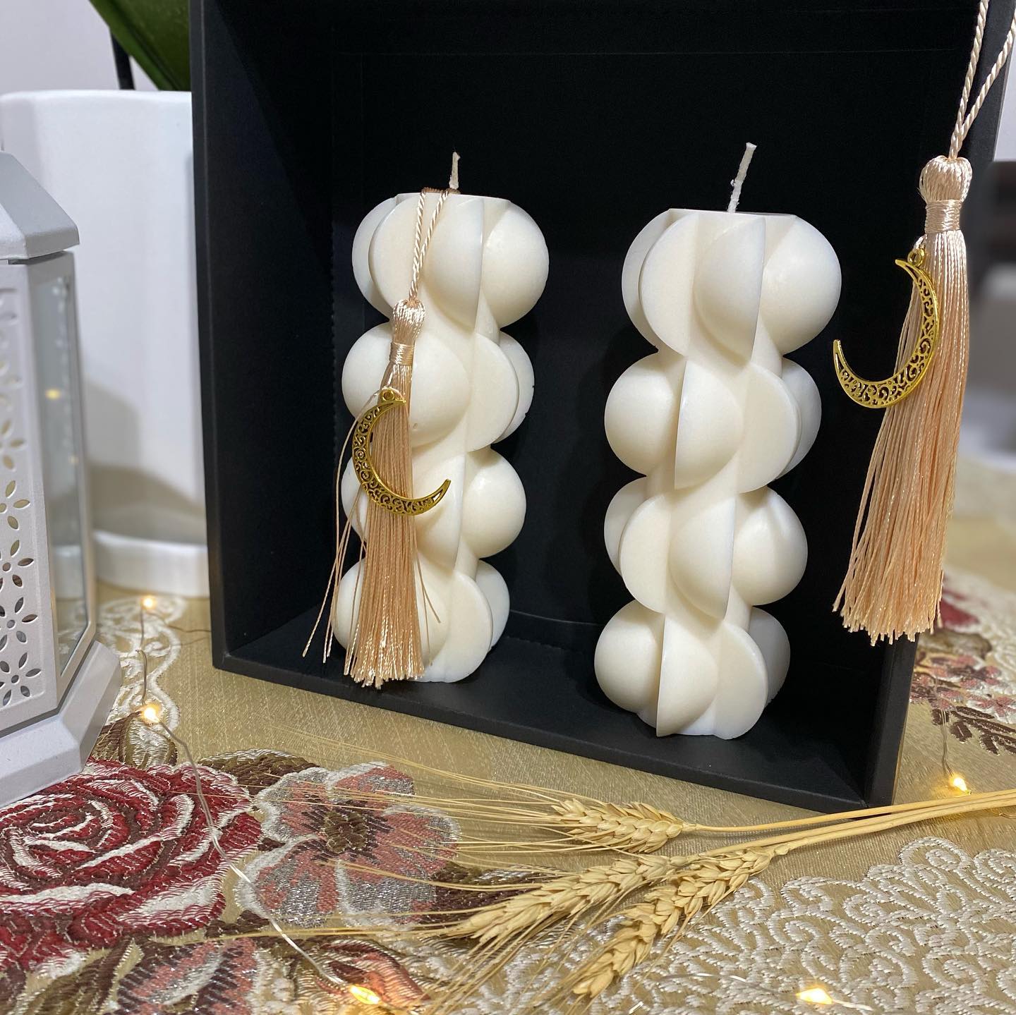 White sculptural candles displayed in a gift box with a crescent tassel